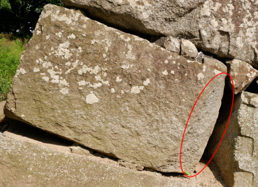 石垣のうち1ブロックをアップで撮った写真に、石尻の部分を示す赤丸の印をつけたもの。この写真では石の右端が石尻である。